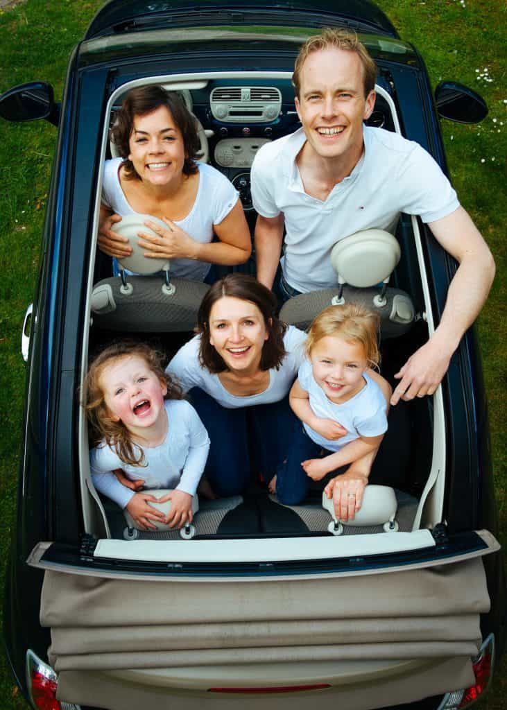 Photo of a family in a convertible car happy smiling